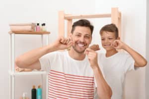 Little boy and his father flossing teeth in bathroom