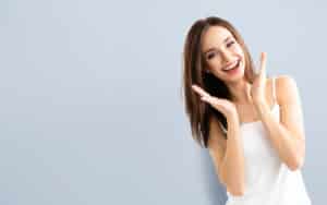 image of a girl in white top smiling with her hands in her face.